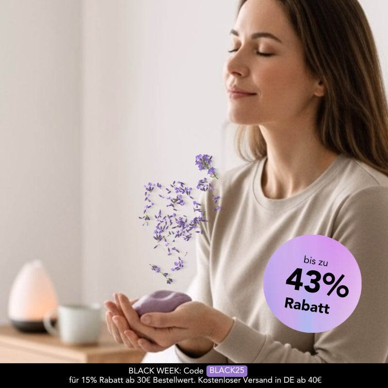 Frau atmet mit geschlossenen Augen entspannt durch und hält dabei die Zendou Duftknete in beiden Händen, aus der Lavendelblüten zu ihr aufsteigen.