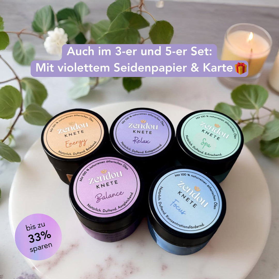 Alle 5 Sorten der Zendou Duftknete auf einem Tisch, im Hintergrund Pflanzen und Kerzen